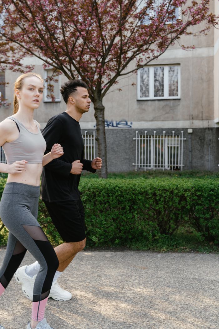 services-01 A couple jogging together on an outdoor path in spring, promoting fitness and wellness.